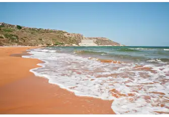 Feel the warm sand between your toes as you stroll down one of Gozo's red-sand beaches
