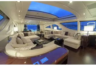 Looking aft across the lounge. To the right of shot there is a pop-up TV and steps leading to the lower deck guest accommodation