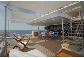 Open-air dining shaded by the overhang and a sun lounge aft with optional shade from removable awnings