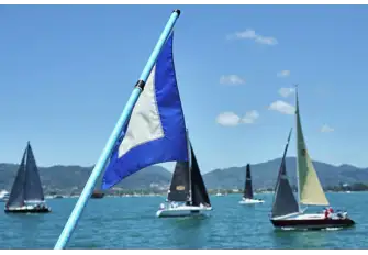 Competing yachts sailing past the committee boat, waiting for the course to be posted